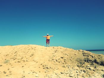 Man standing on beach against clear blue sky