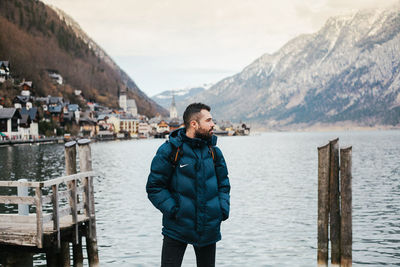 Portrait of young man standing on mountain against sky