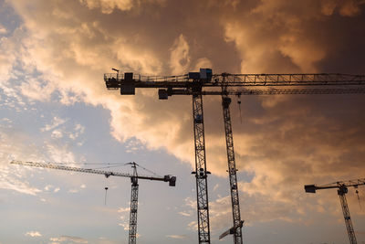 Low angle view of crane against cloudy sky