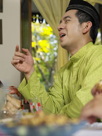 Side view of man having food at home during traditional festival