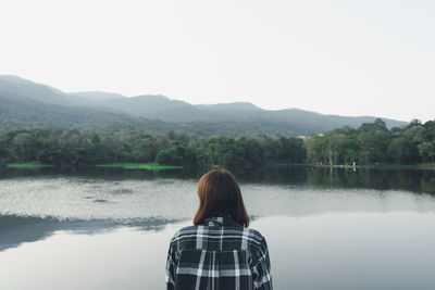 Rear view of woman looking at lake against sky