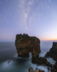 Rock formation in sea against sky at night