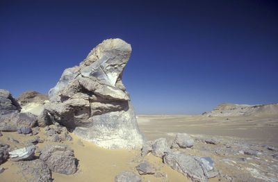 Low angle view of rock formations in desert against clear blue sky