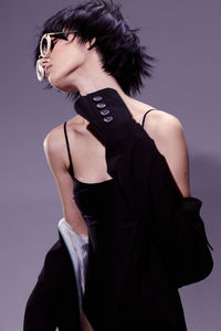 Portrait of young woman standing against wall