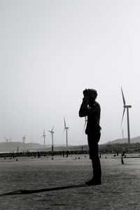 Man with umbrella on sea against clear sky