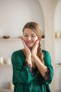 Portrait of young woman standing against wall