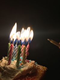 Close-up of lit candles on cupcake against black background