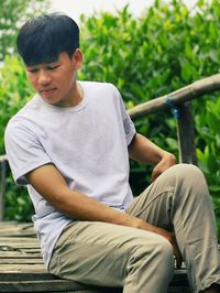 Young man sitting on footbridge