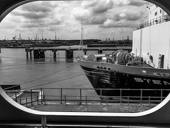 Boats moored at harbor against sky in city