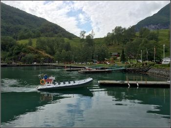 Boats in river against cloudy sky