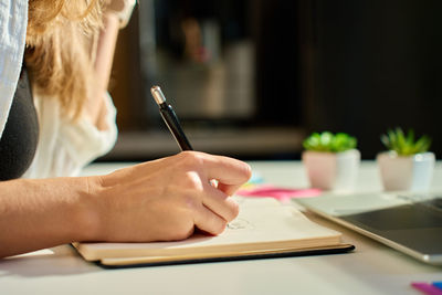 Illustrator drawing sketches in notebook at home office desk