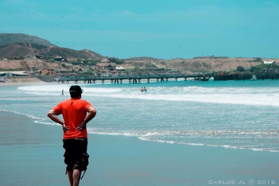 water, mountain, rear view, sea, leisure activity, lifestyles, full length, standing, scenics, tranquil scene, blue, beauty in nature, tranquility, beach, nature, vacations, mountain range, casual clothing