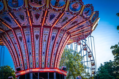 Low angle view of chain swing ride against blue sky