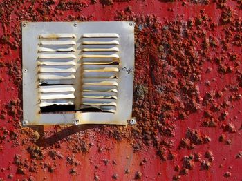 Air duct on weathered red wall during sunny day