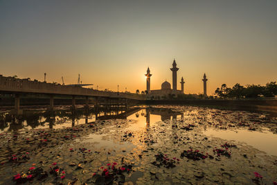 View of temple by building against sky during sunset