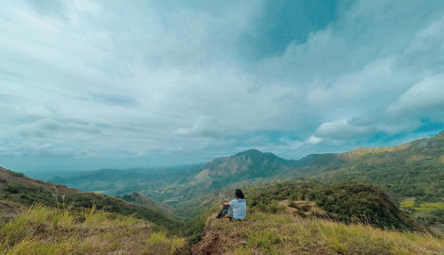 Rear view of man standing on mountain against sky