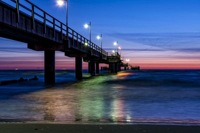 Pier over sea against sky at sunset