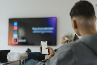 Teenage boy with smart phone app sitting in living room at home