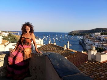 Woman standing by sea against sky in city