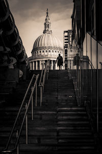Man on staircase by building in city against sky