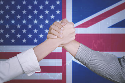 Digital composite image of business people giving handshake against flags