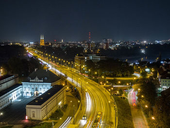 High angle view of illuminated street amidst buildings in city at night