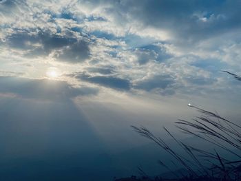 Low angle view of sunlight streaming through clouds