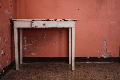 Old rusty metal table against orange wall in room