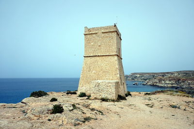 Castle by sea against clear blue sky