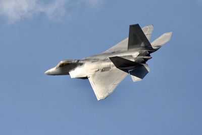 Low angle view of fighter plane flying in blue sky