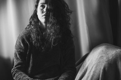 Young woman looking away while sitting at home