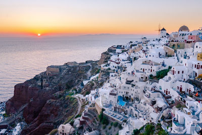 High angle view of sea and buildings against sky during sunset