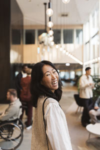 Side view portrait of happy businesswoman laughing while standing in convention center lobby