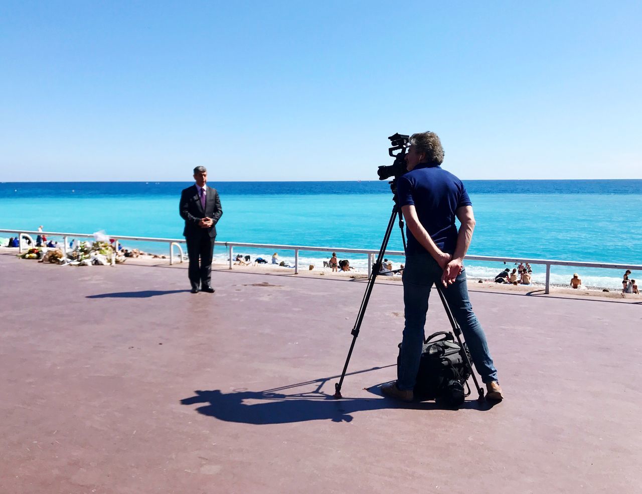 MEN PHOTOGRAPHING AT BEACH AGAINST CLEAR SKY