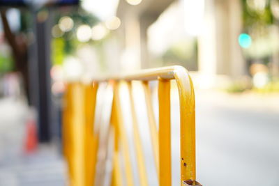 Close-up of yellow railing on street