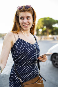 Sceptic woman listening to music on street