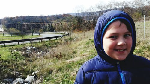 Portrait of smiling boy standing against trees