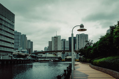 Bridge over river by buildings against sky