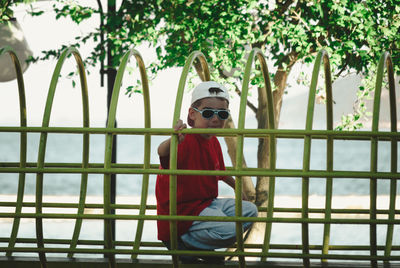 Portrait of boy wearing sunglasses crouching on jungle gym at park