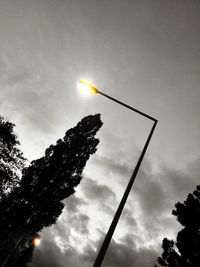 Low angle view of trees against cloudy sky