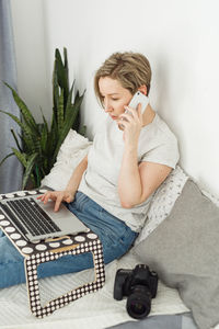 Young woman using laptop while sitting on bed at home