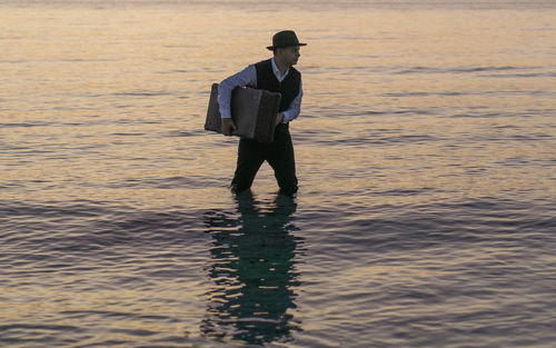 Man with briefcase wading in sea