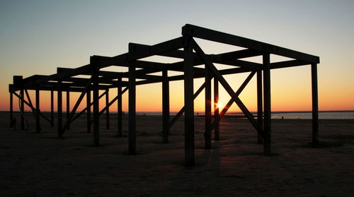Silhouette built structure on beach against clear sky