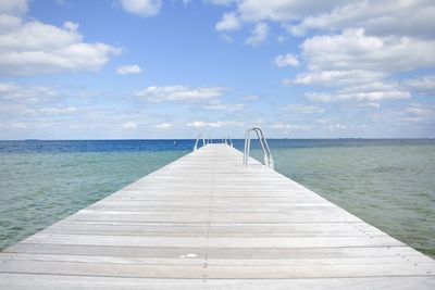 Pier on sea against cloudy sky