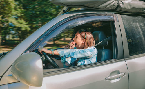 Young woman yawning while traveling in car
