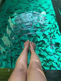 Low section of woman relaxing in swimming pool