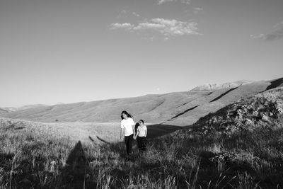 Rear view of women standing on mountain against sky