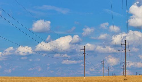 Low angle view of electricity pylon on field against sky