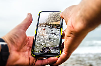 Midsection of man using mobile phone at beach