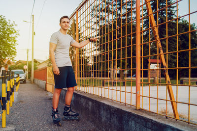 Full length of man roller skating on footpath by metal grate